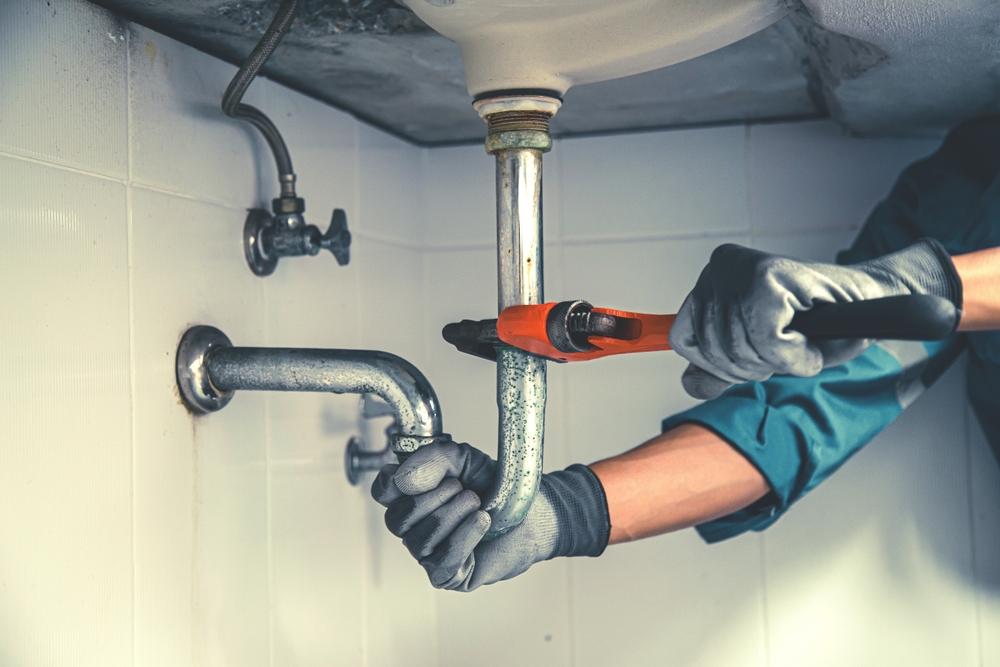 Technician,plumber,using,a,wrench,to,repair,a,water,pipe